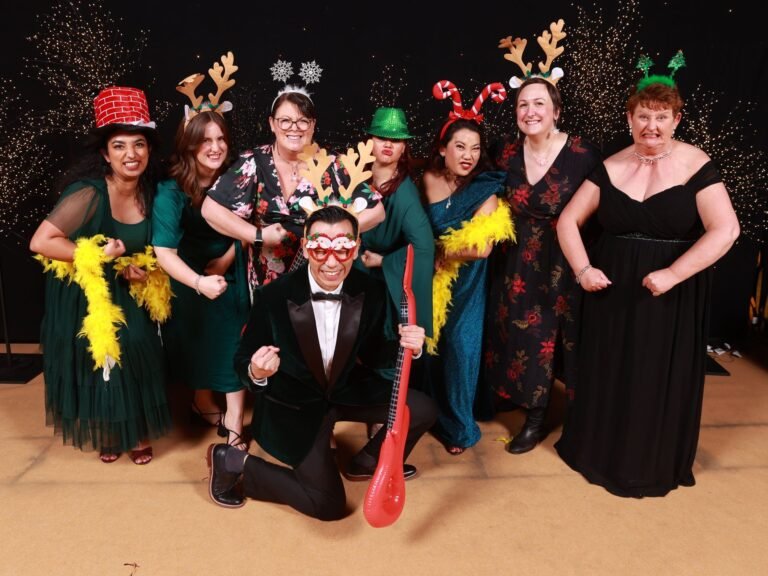 A lively group poses in festive attire at a memorable Christmas party event, showcasing joy and celebration.